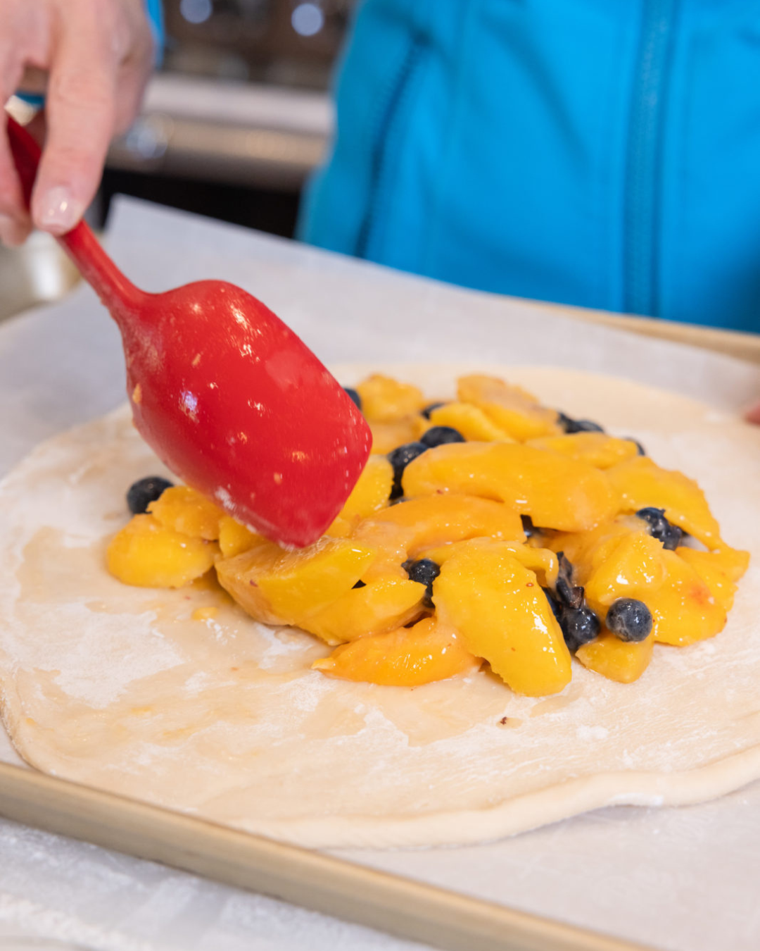 Tiffany putting the peaches and blueberry filling on the pastry dough, the perfect dessert for peach season