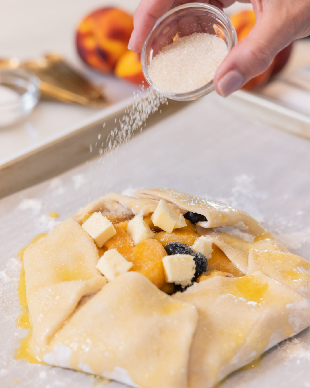 tiffany adding sugar to the top of the uncooked galette, the perfect dessert  for peach season